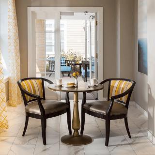A modern dining area featuring a glass-topped table with two stylish chairs in a well-lit space.