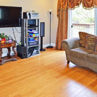 A cozy living room with a television and sound system, featuring a comfortable sofa and wooden flooring.