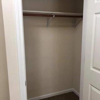 An empty closet with a single hanging rod and shelf.