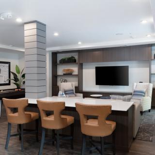 A modern open living room featuring a kitchen island with bar stools and a wall-mounted TV.