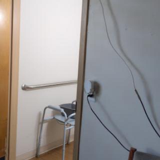 A view of a room with a door, a walker in the corner, and some cables along the wall.
