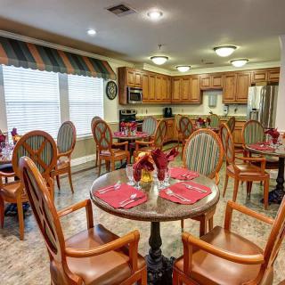 A cozy dining room with tables set for a meal, adjacent to a spacious kitchen.