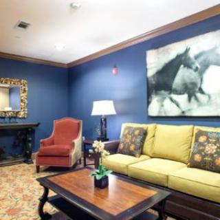 A cozy living room featuring a yellow sofa, red armchair, and a coffee table with decorative items, accompanied by wall art and a mirror.