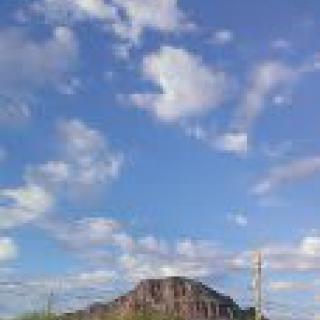 A scenic view of a mountain under a blue sky with scattered clouds.