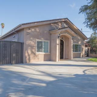 A single-story residential house with a spacious driveway on a clear, sunny day.