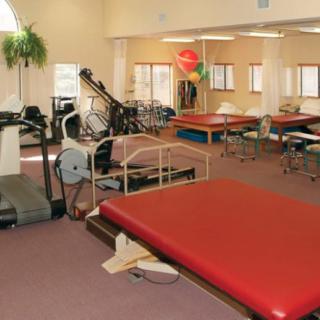 A physical therapy room equipped with exercise machines and therapy tables.