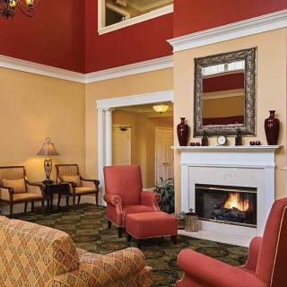 A cozy living room with red and beige walls, featuring a fireplace, armchairs, and elegant decor.
