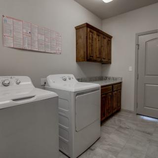 A spacious laundry room with a washing machine, dryer, and wooden cabinets.