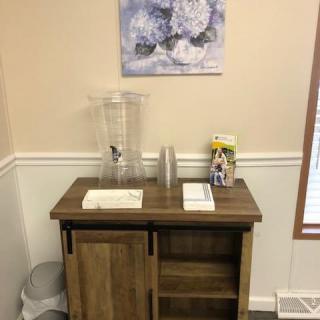 A small cabinet with a water dispenser and cups in a decorated room.