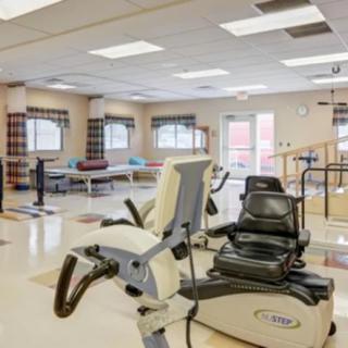 A rehabilitation room equipped with exercise machines and therapy tables.