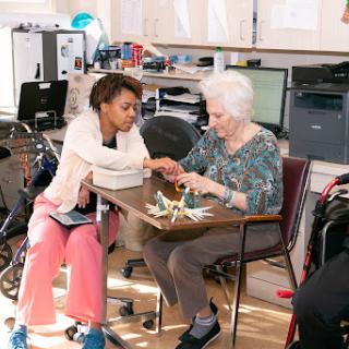 A caregiver engages with an elderly woman, fostering connection and support through shared activities.