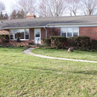 A single-story ranch-style brick house with a well-maintained front yard and lawn.
