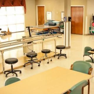 An empty rehabilitation room equipped with exercise bars and seating for physical therapy.