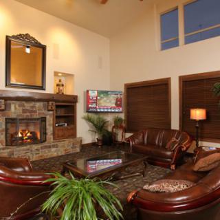 A cozy living room with a fireplace and leather furniture, featuring warm lighting and modern decor.