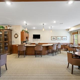 A spacious and modern lounge area featuring a bar, comfortable seating, and bright lighting.