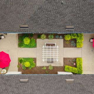 Aerial view of a landscaped courtyard with a patio and red umbrellas.