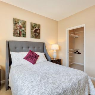 Cozy bedroom with a neatly made bed, decorative wall art, and an adjoining closet.