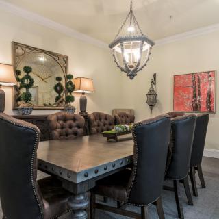 Elegant dining room with a large table, upholstered chairs, and a central chandelier.