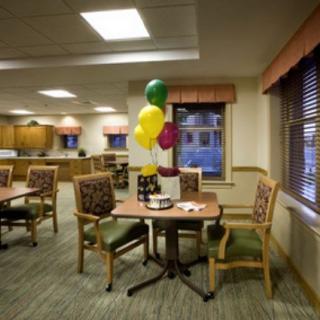 A cozy dining area with tables and chairs, decorated with colorful balloons.