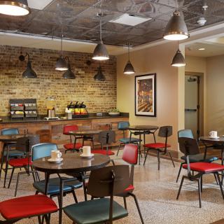 A cozy cafe interior with colorful chairs and an exposed brick wall.