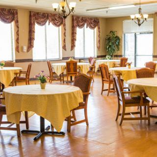 A spacious and well-lit dining area featuring neatly arranged tables with yellow tablecloths.