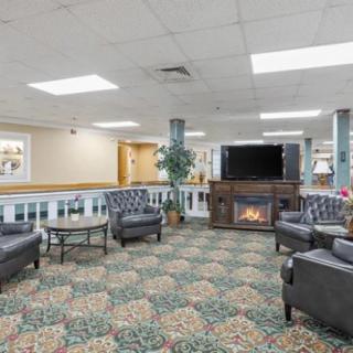 A cozy lobby with armchairs, a coffee table, and a fireplace near a television.