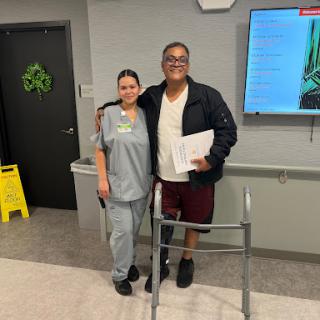 A patient standing with a nurse, showcasing the support and care during rehabilitation.