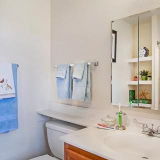 A tidy bathroom with a mirror, sink, and neatly arranged towels.