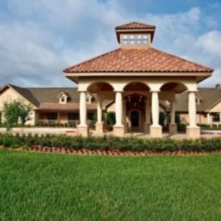 A large building with a columned entrance and a well-manicured lawn under a blue sky.