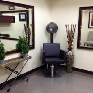 A cozy salon corner with mirrors, a dryer chair, and decorative plants.