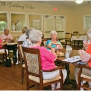 A group of seniors enjoying a meal and conversation in a dining area.