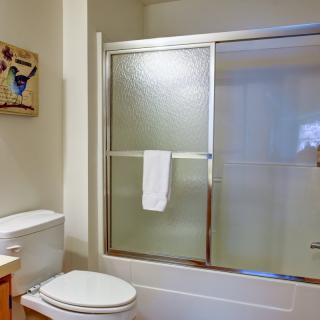 A clean and modern bathroom with a glass shower door and a towel hanging.