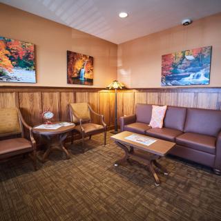 A cozy waiting room with a sofa, chairs, and artwork on the walls.