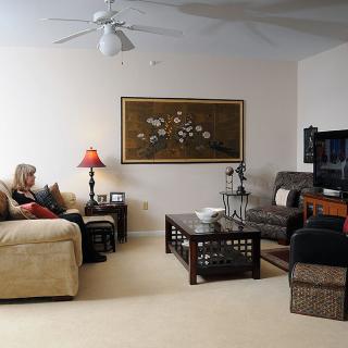 A cozy living room with a woman sitting on a sofa, facing the television.