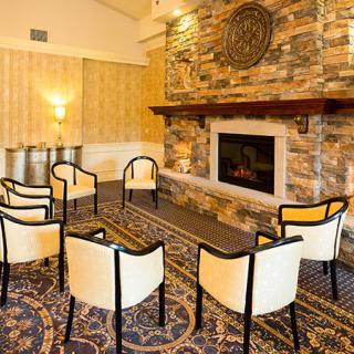 A cozy seating area with chairs arranged around a stone fireplace.