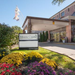 Entrance to a building with a sign and well-maintained landscaping.