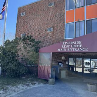 The main entrance of Riverside Rest Home, featuring the flag and signage.