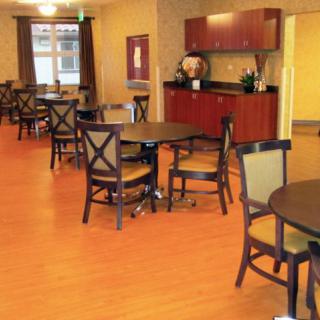 A well-furnished dining area with wooden tables and chairs on a wood floor.