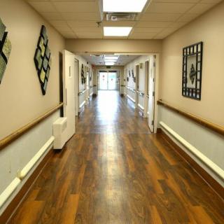 A well-lit hallway with wooden flooring and artwork on the walls.