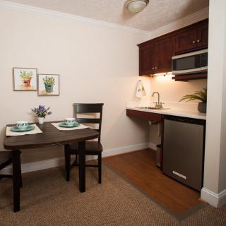 A compact kitchenette with a small dining area, featuring a table set for two.