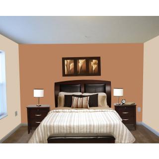 A well-decorated bedroom with a central bed flanked by nightstands and lamps, enhanced by warm wall colors and framed artwork.