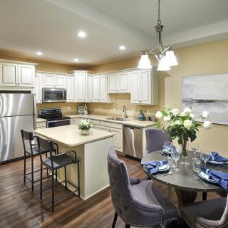 A modern kitchen and dining area featuring stainless steel appliances, an island counter, and a cozy dining table with chairs.