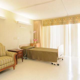A brightly lit hospital room with a single bed, chair, and curtains.