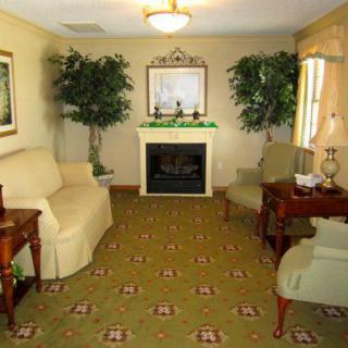 A cozy living room with a fireplace, sofas, and decorative plants.