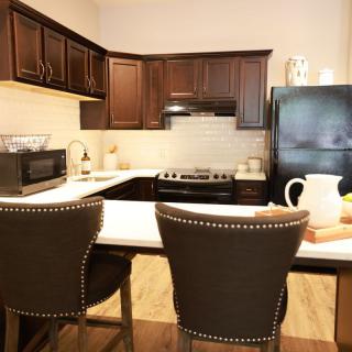 A modern kitchen interior with dark wood cabinets and a breakfast bar.