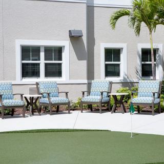 Outdoor seating area with a putting green and palm tree.