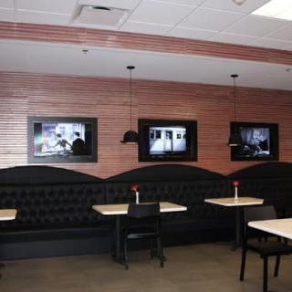A modern restaurant interior featuring booth seating and wall-mounted TVs.