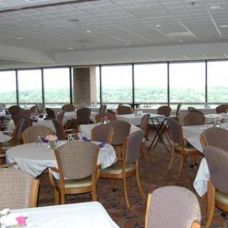A spacious dining area with multiple tables and chairs, featuring large windows offering an expansive view.