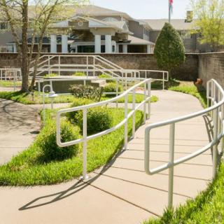 An outdoor ramp with railings leading to a building, surrounded by greenery.