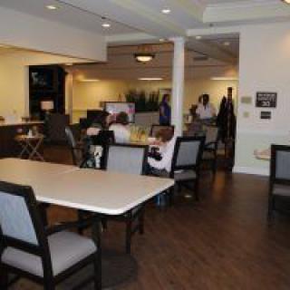 A modern dining area with tables and chairs, where people are gathering.